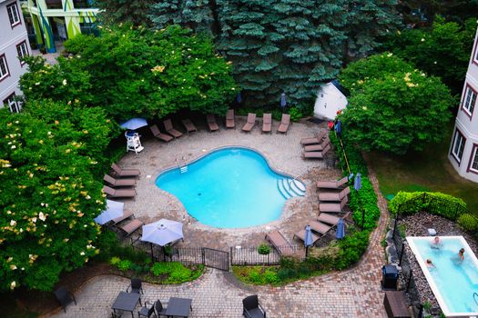 Charming aerial shot of a swimming pool surrounded by lush greenery in Mont-Tremblant, Canada.