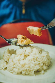 Close-up of a warm rice dish served with succulent chicken pieces, set in a cozy dining environment.
