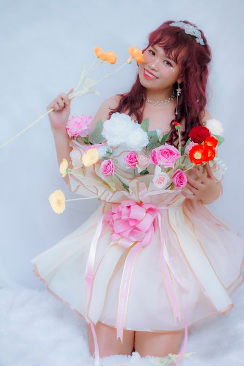 Free A smiling woman with red hair holding a vibrant bouquet of flowers against a white background. Stock Photo