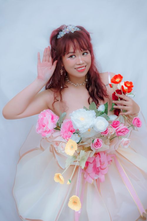 Free Smiling bride holding a vibrant bouquet, showcasing bridal fashion in a studio setting. Stock Photo