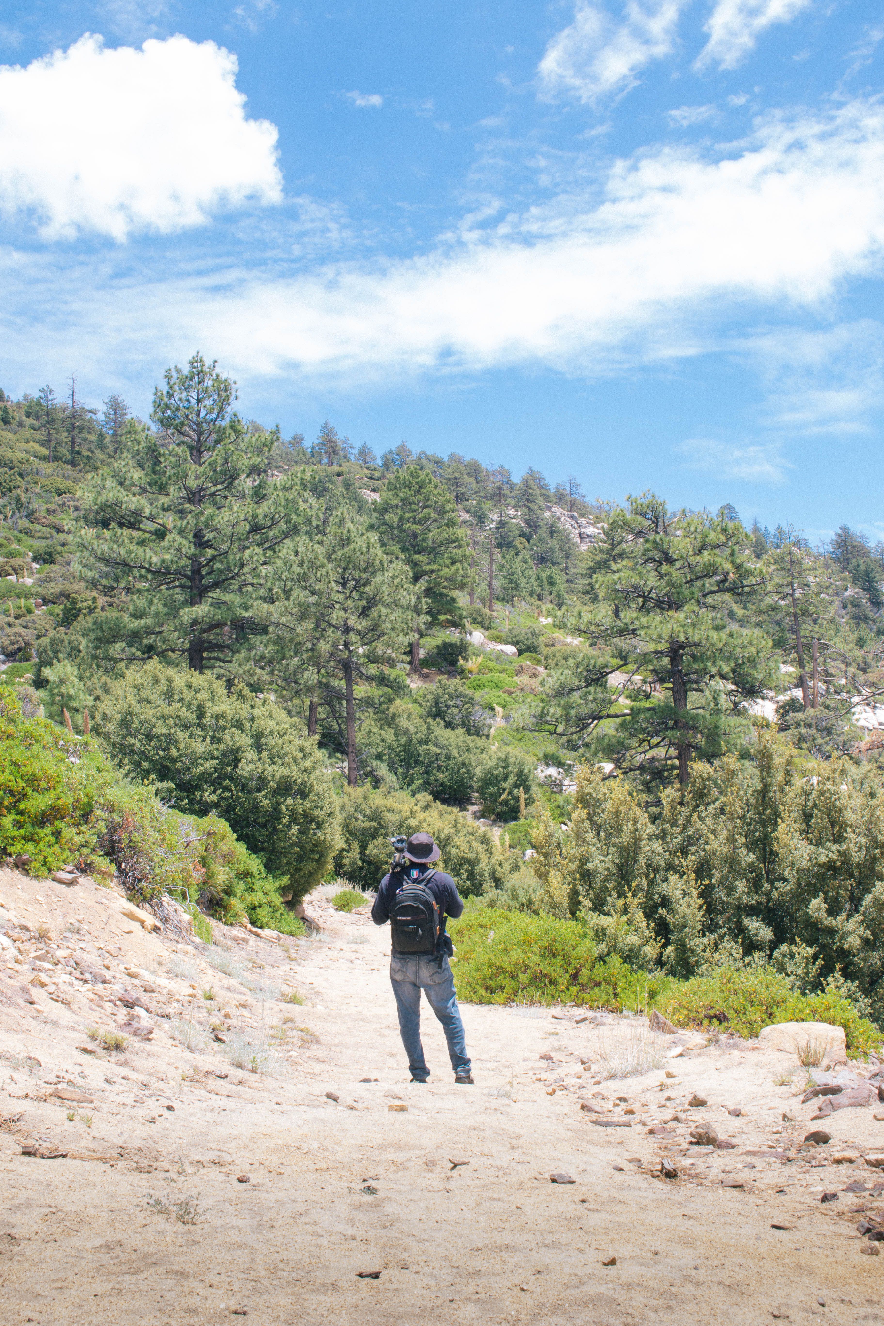 A man is walking down a dirt path with a backpack · Free Stock Photo