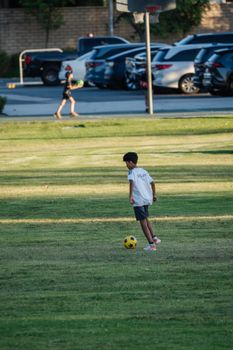 A young boy playing soccer on a grassy field during the day, enjoying the outdoors.