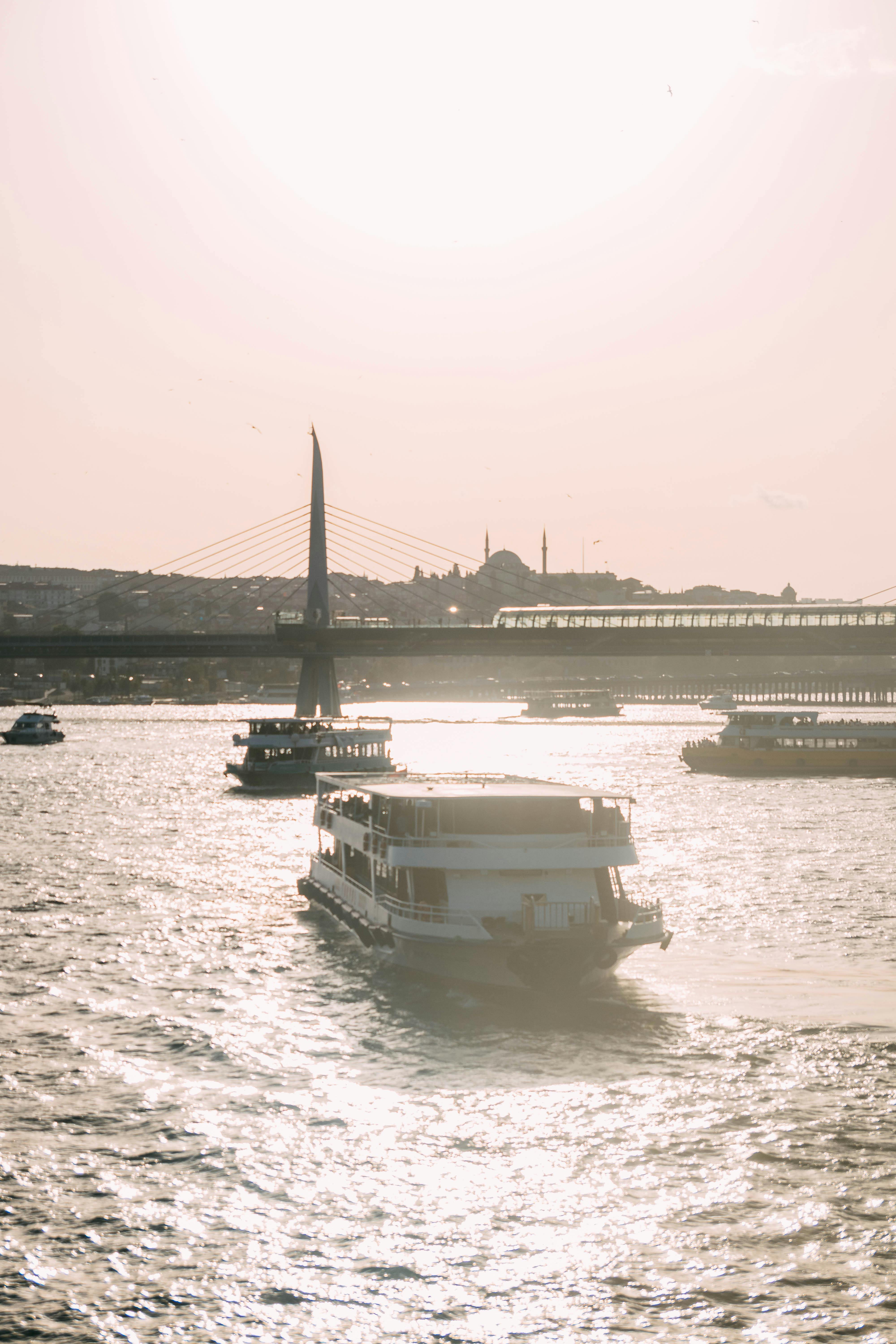 Gratuit Bateaux naviguant sur la scintillante Corne d'Or avec un pont pittoresque au coucher du soleil. Photos