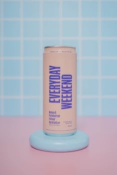 A vibrant pink can of mango and passionfruit hard seltzer in a modern studio setting with a pastel backdrop.