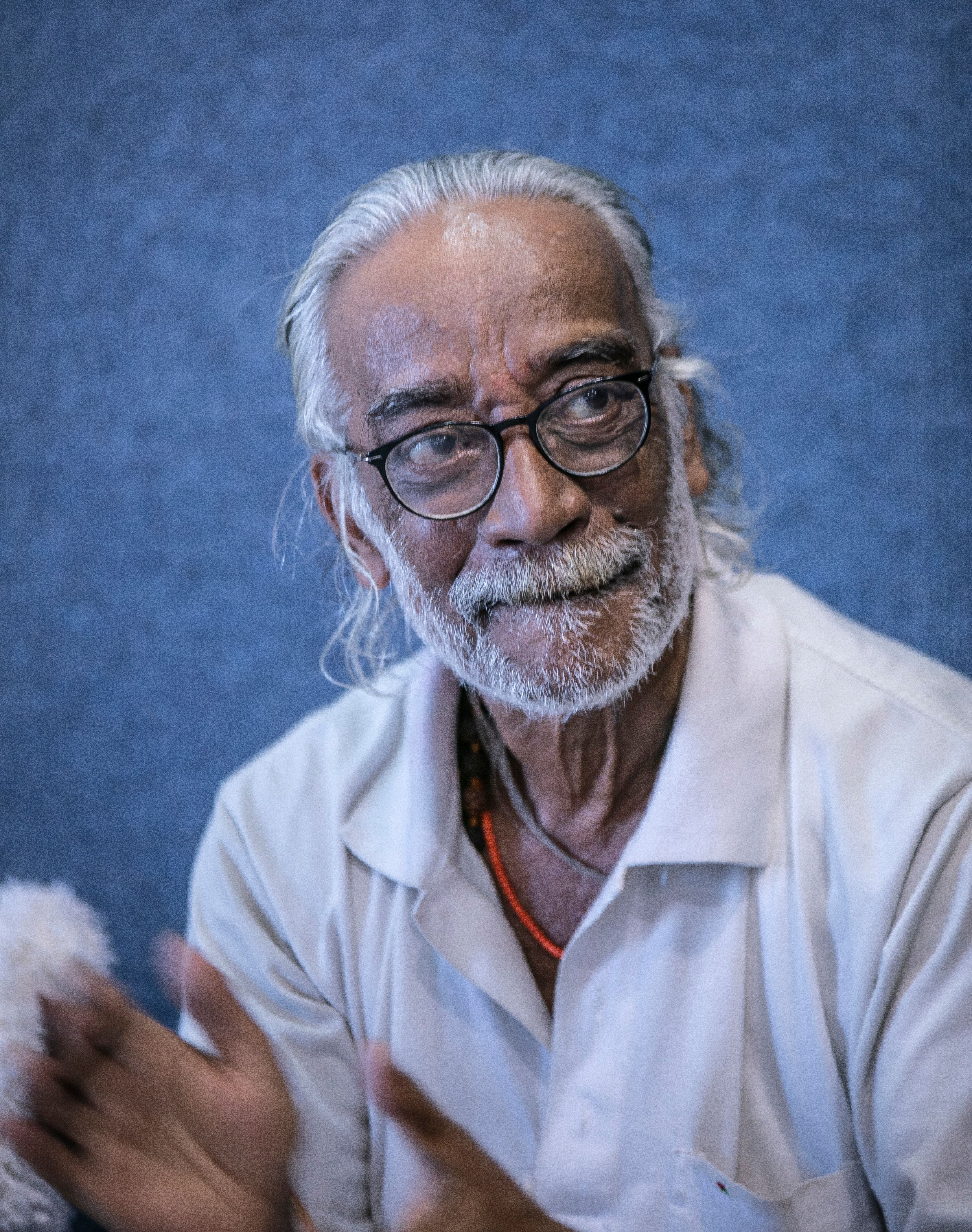 Captivating portrait of an elderly man with glasses and white hair, captured clapping indoors.