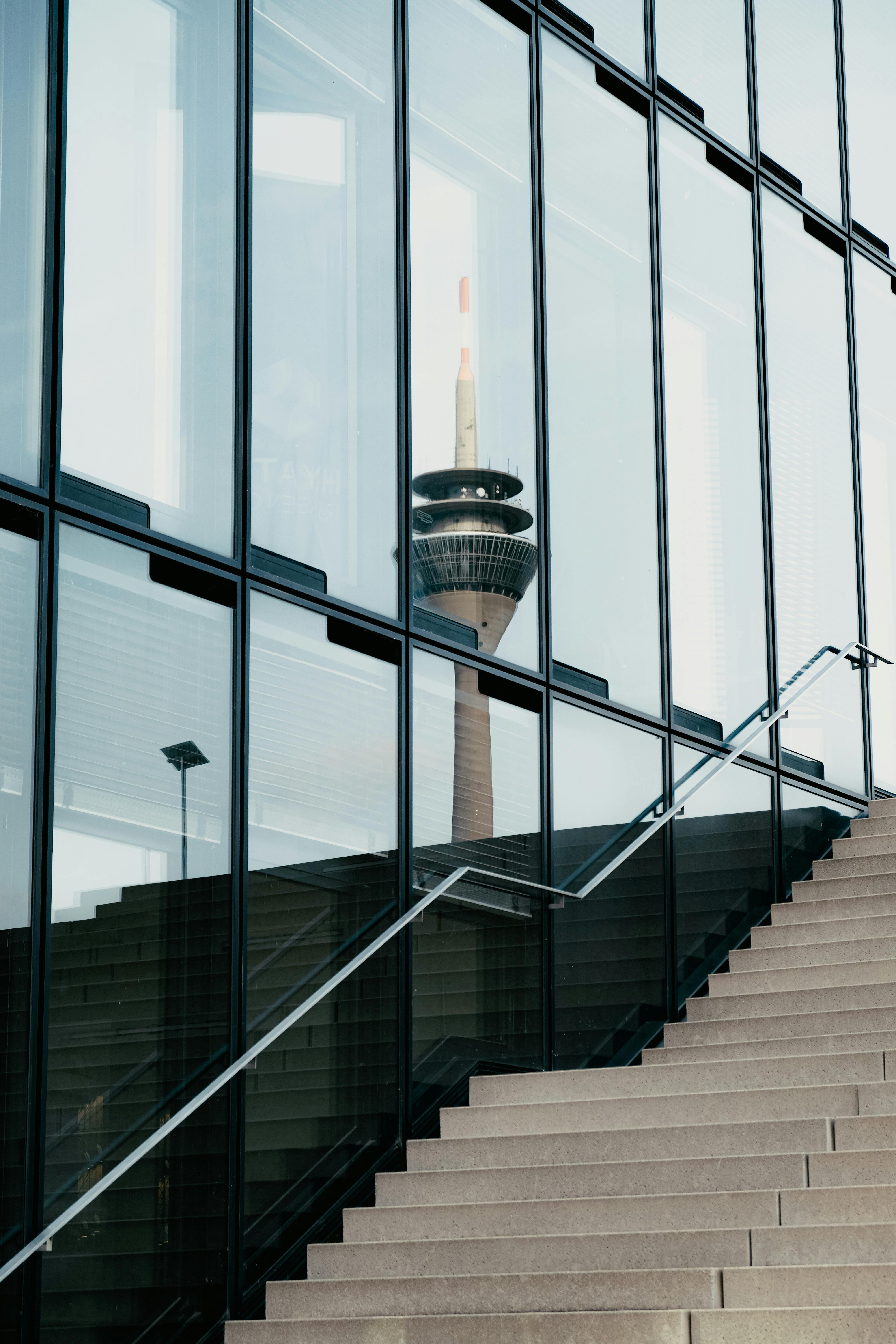 Capture of Düsseldorf's iconic tower reflected in a modern building's glass facade.