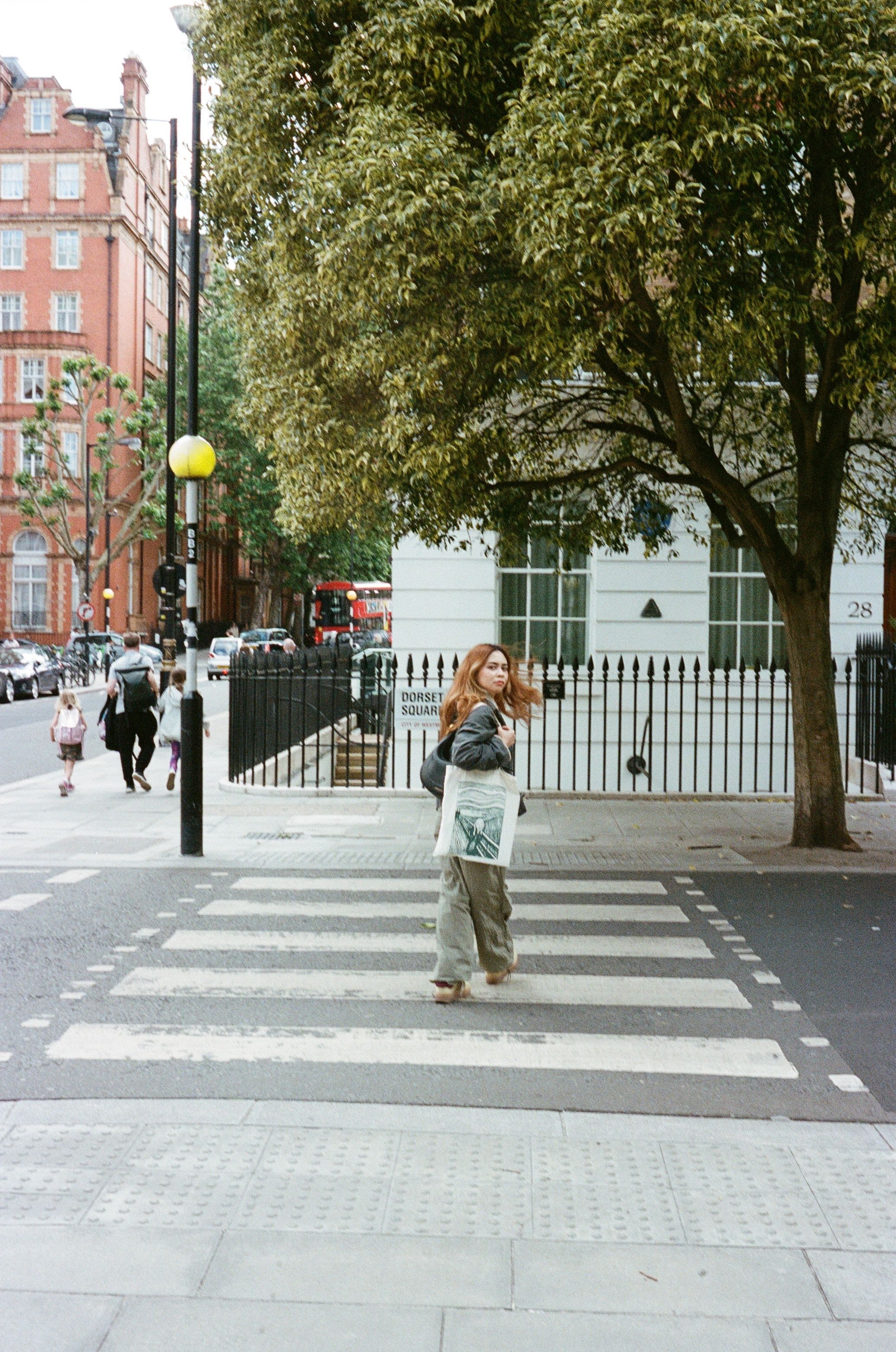 A woman walking across a street in london · Free Stock Photo