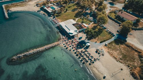 Free Aerial view of a sunny beach resort with sunbeds and parasols along the shoreline. Stock Photo