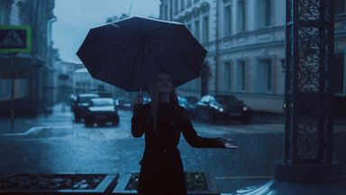 A pedestrian under an umbrella in heavy rain