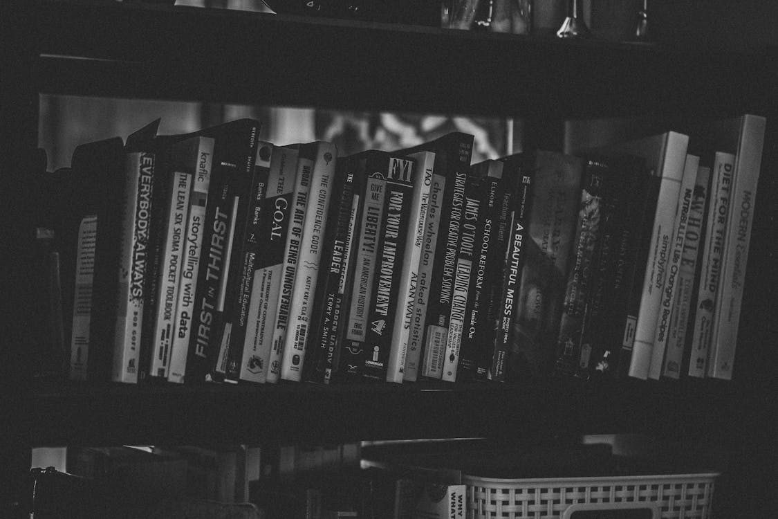 Free Grayscale Photography of Books Stacked in Shelf Stock Photo