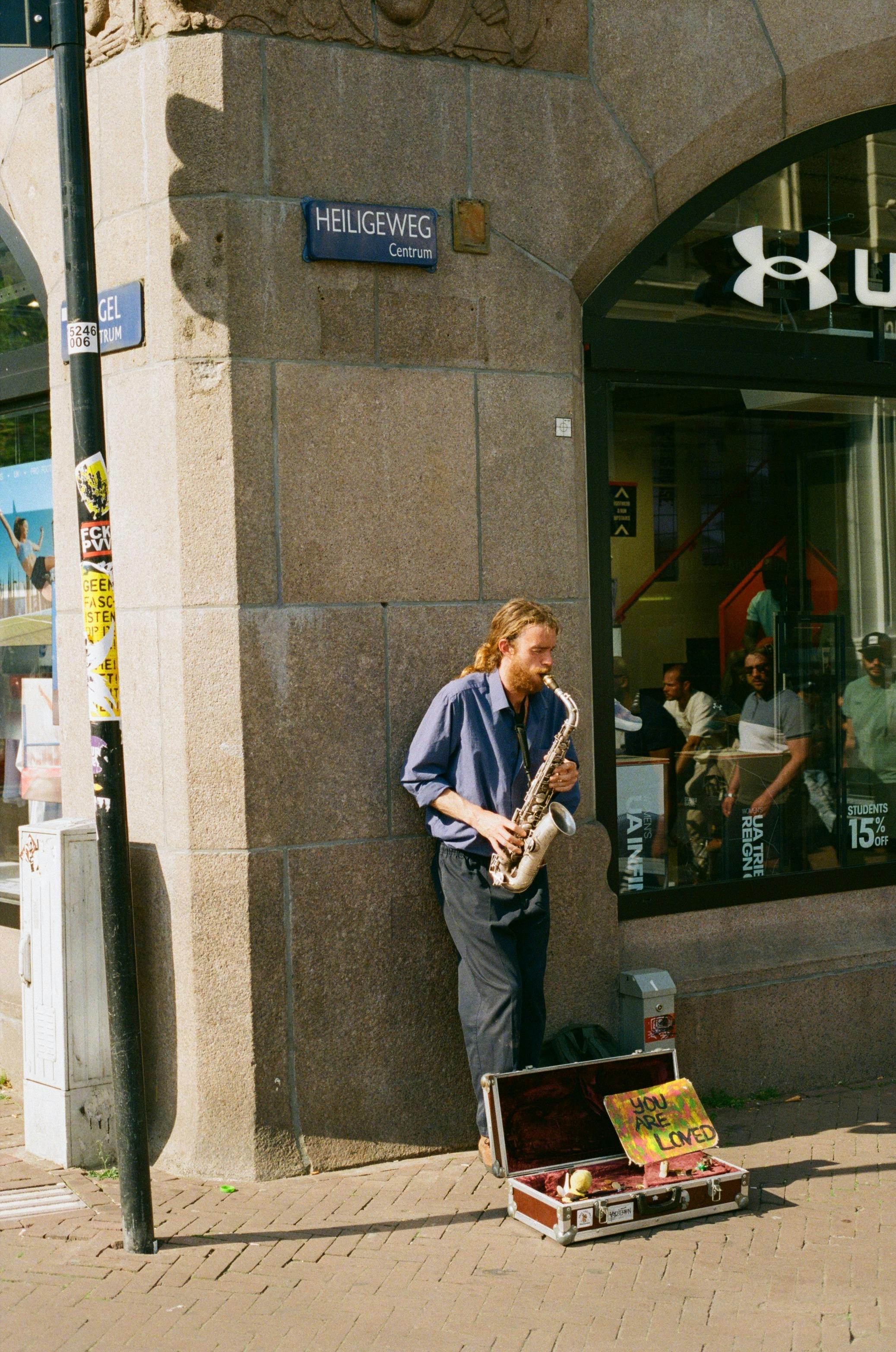 A musician plays saxophone on a street corner, adding life to the urban setting.
