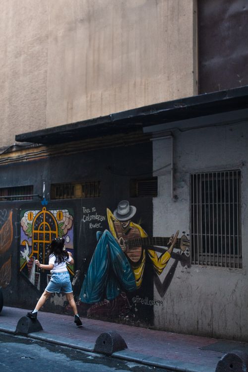 Free A young woman walks past vibrant street art in İstanbul's urban alleyway. Stock Photo