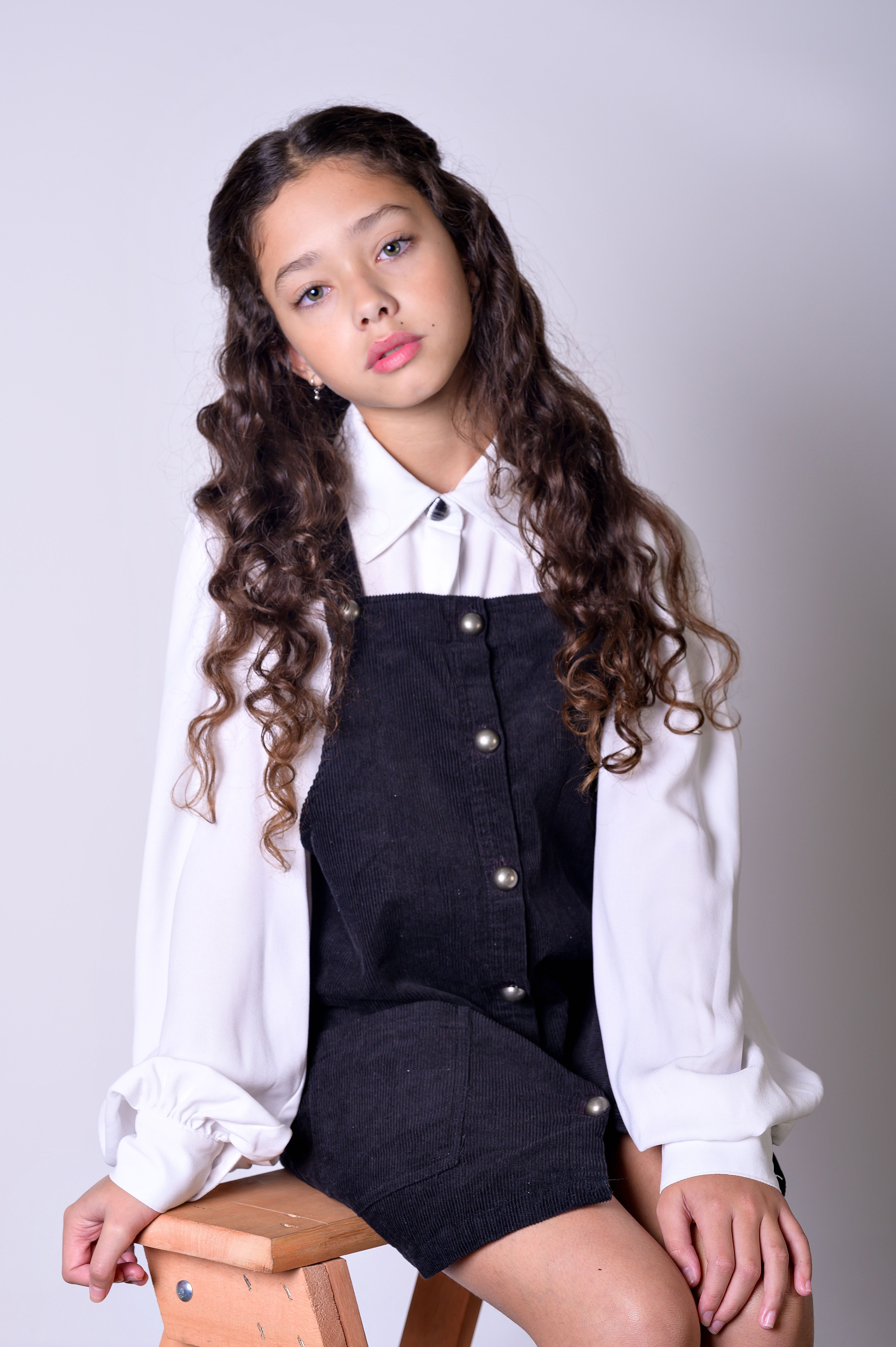 Elegant studio portrait of a girl with long brown hair in a fashion outfit.