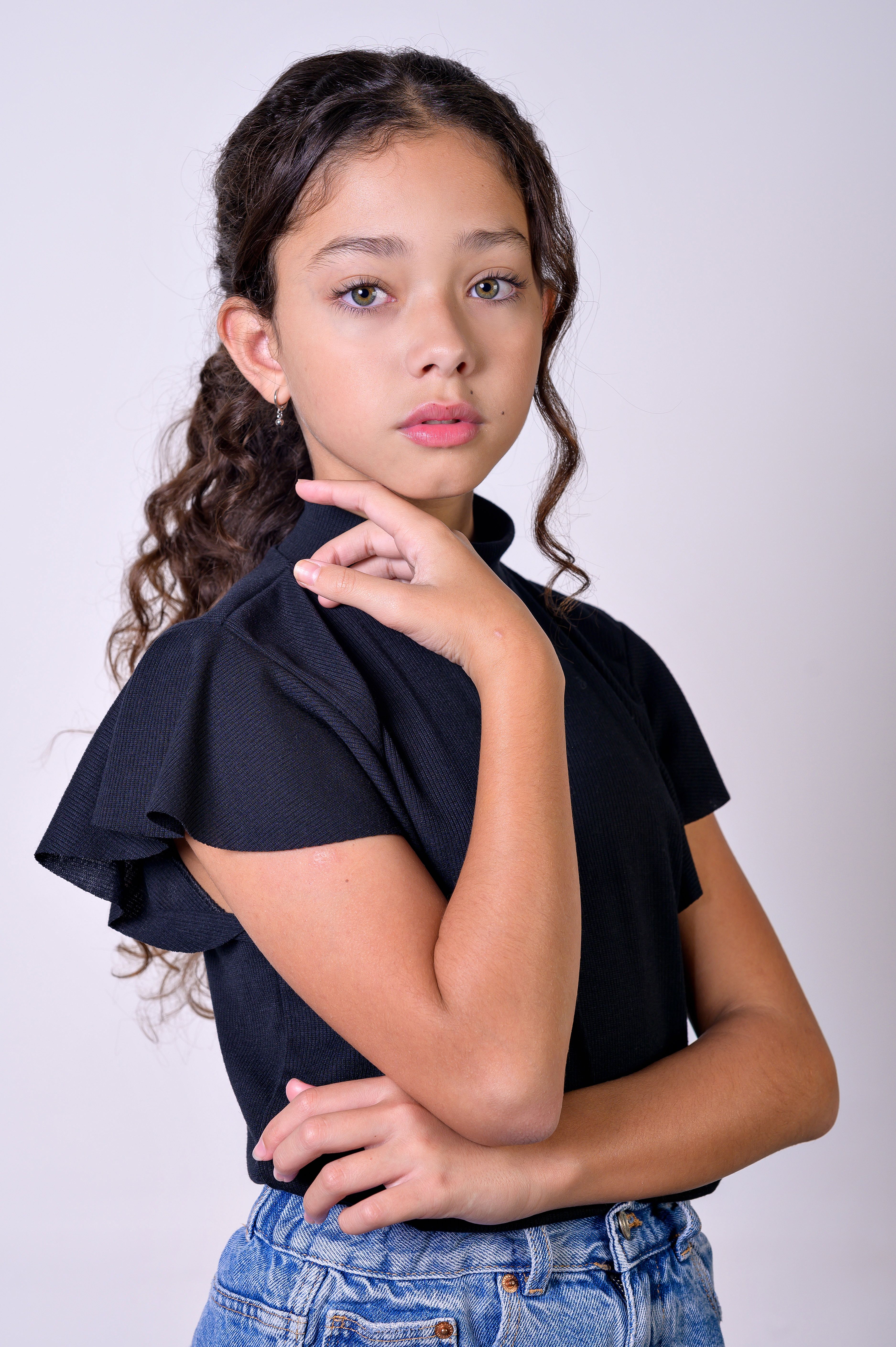 Studio portrait of a stylish young girl posing confidently in fashionable attire with a soft background.