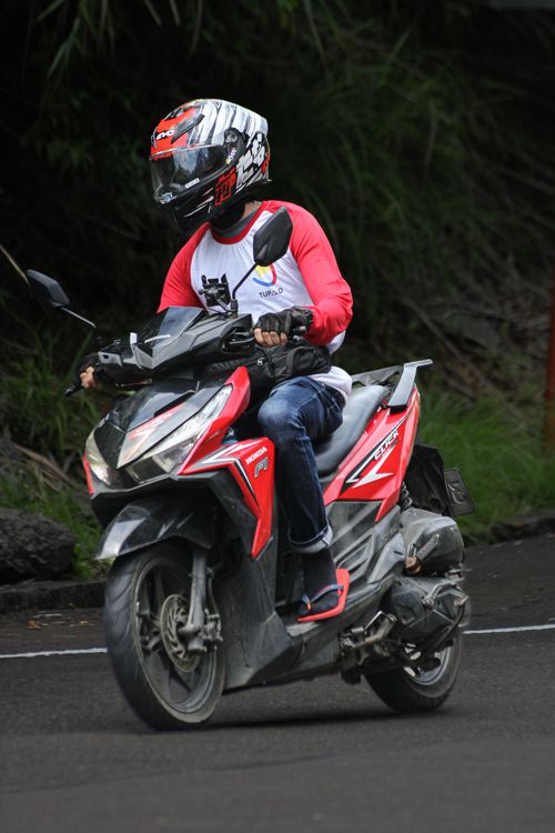 Free Man in helmet riding a red scooter outdoors, showcasing urban travel and adventure. Stock Photo
