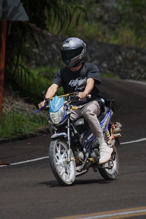 Free A person riding a motor scooter on a winding road, wearing a helmet. Stock Photo