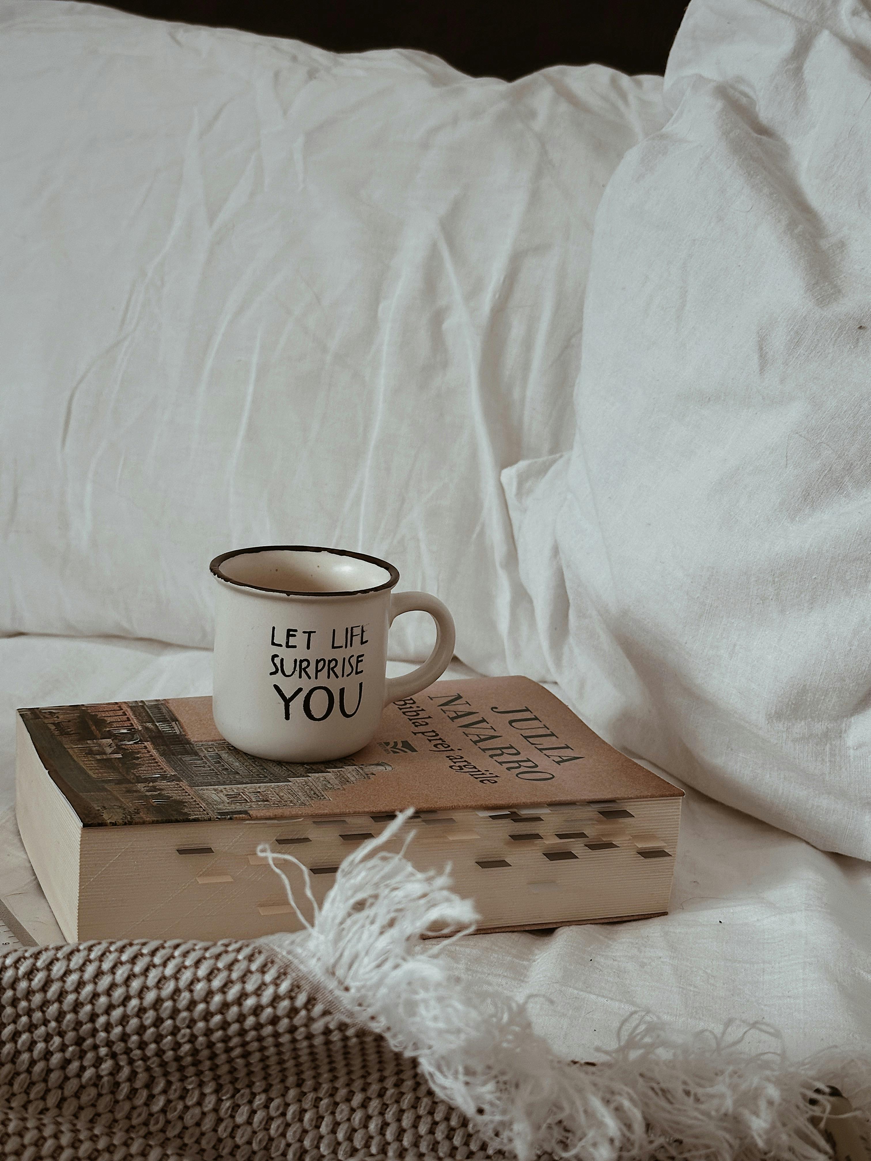 A cozy bedroom scene featuring a mug with a motivational slogan and a book, perfect for peaceful moments.