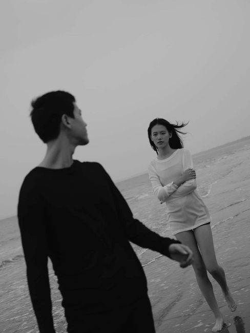 Serene black and white photo of a couple walking along the beach.