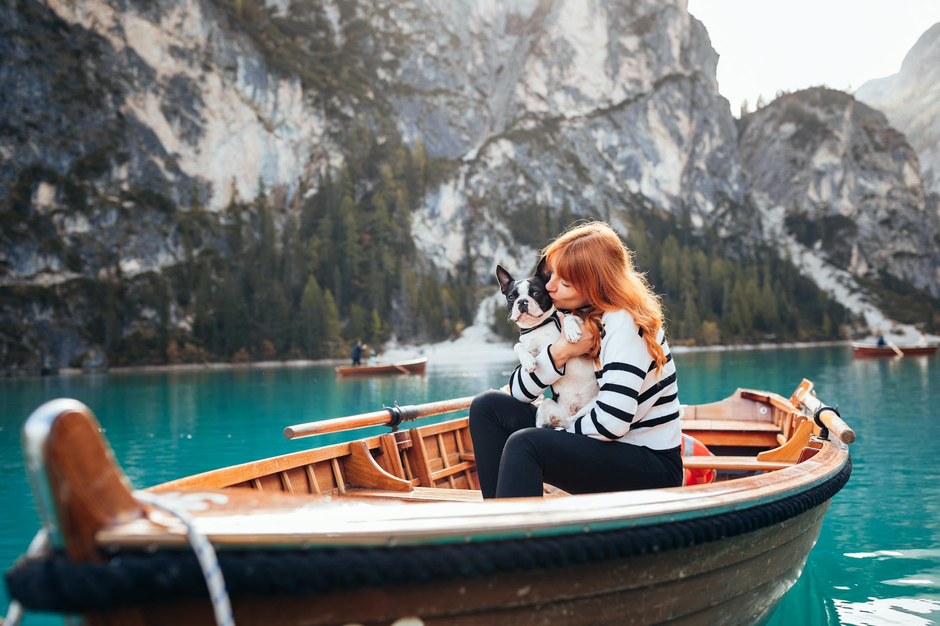 A Woman with Her Dog Sitting on a Boat on a Lake in the Mountains