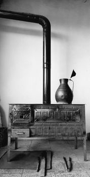 A retro stove with a black pipe and jug in a vintage style kitchen.