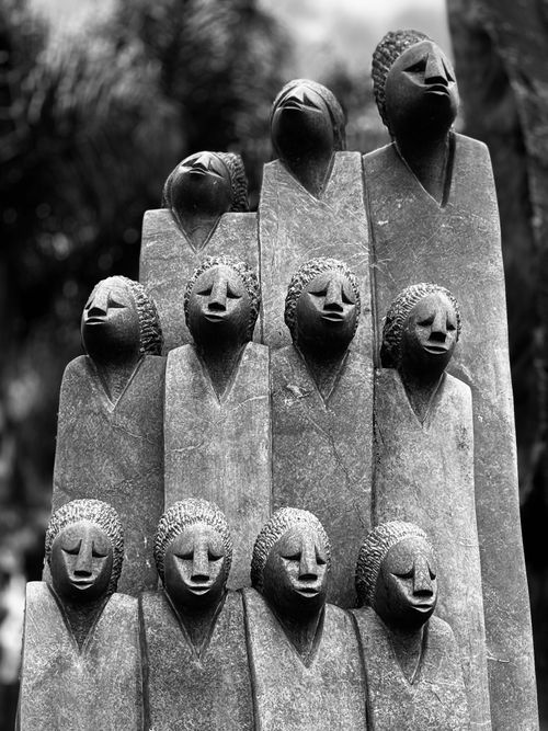 Free Abstract stone sculpture featuring multiple carved heads in a vertical arrangement. Stock Photo