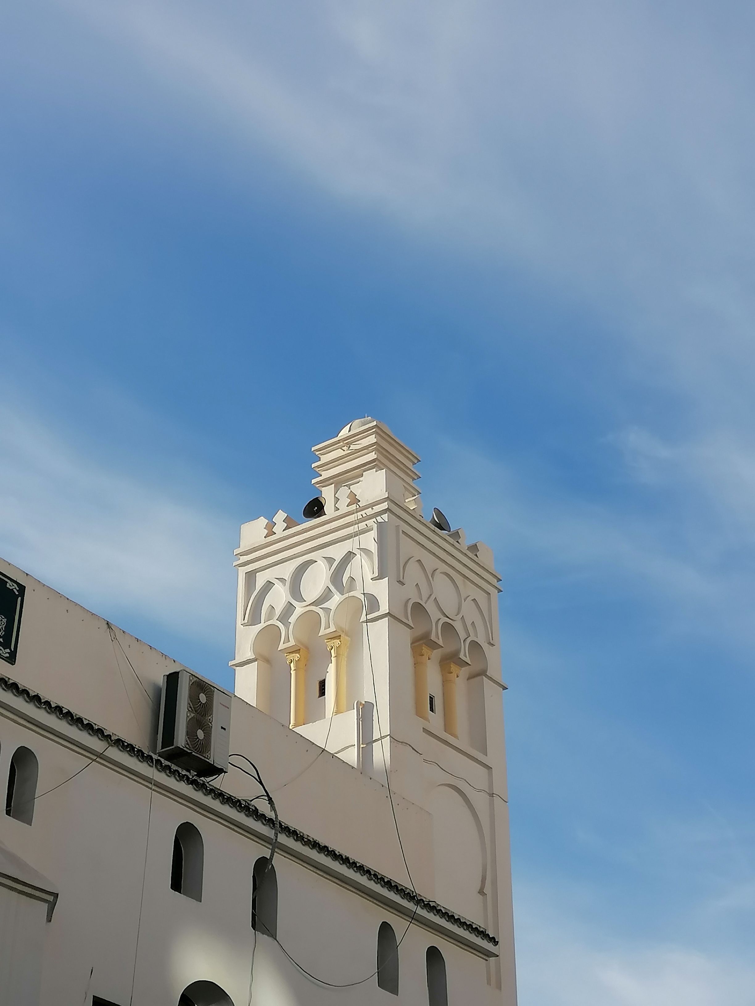 Low angle view of Ali Bitchin Mosque's minaret in Algiers, highlighting architectural elegance against a clear sky.