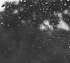 窗户上雨滴的黑白特写图像，营造出喜怒无常的氛围