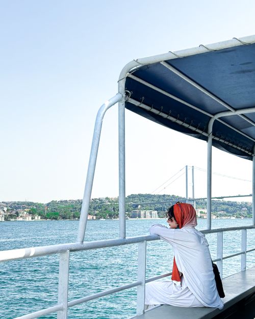 Free A woman in a red shawl enjoys the scenic Bosphorus view in İstanbul, Türkiye. Stock Photo