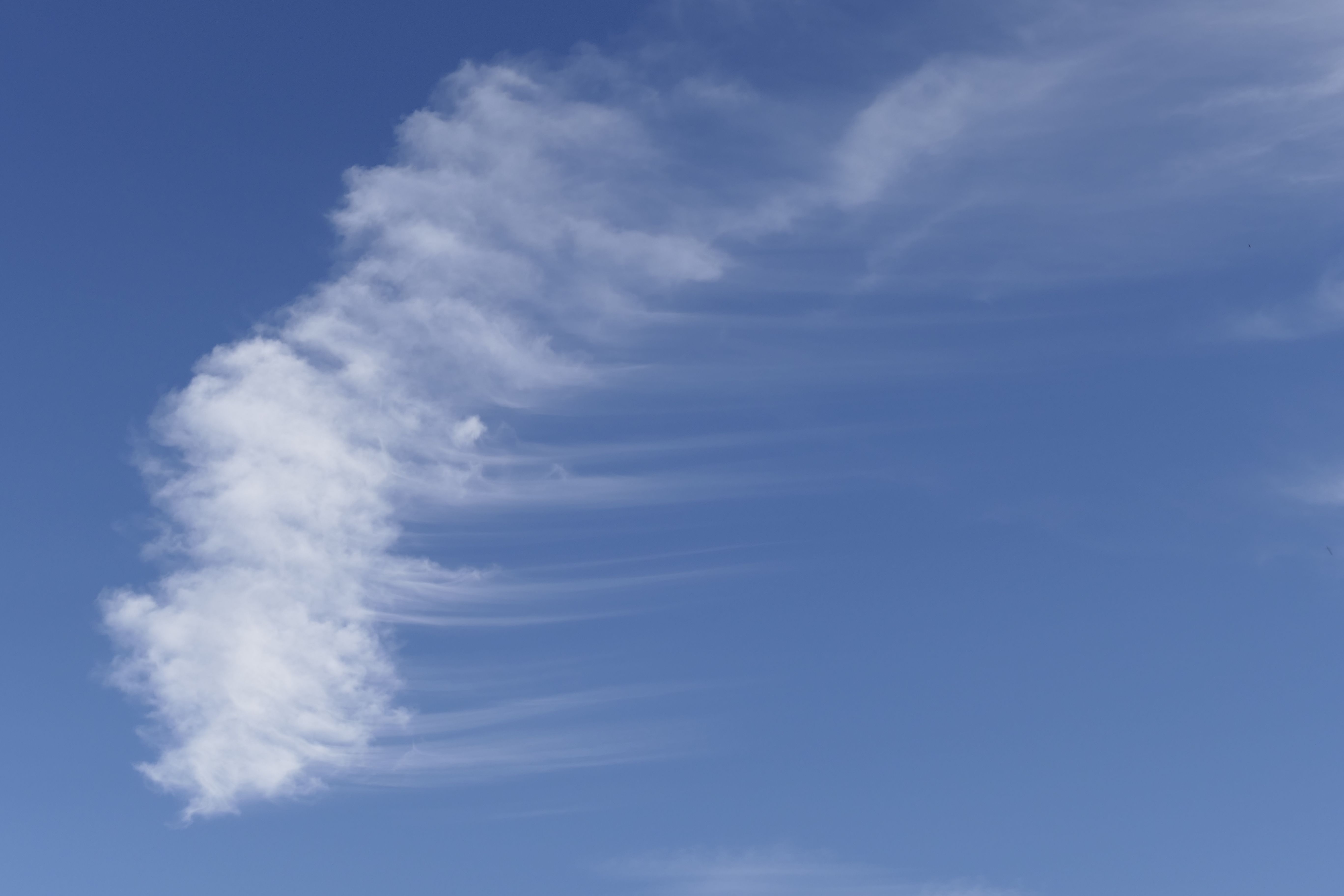 Serene wispy cloud formation set against a vibrant blue sky, perfect for nature and weather themes.