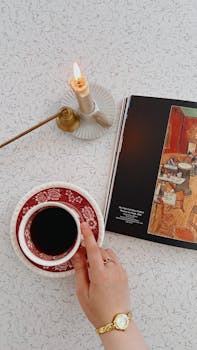 Top view of a coffee cup, book, and candle on a bright surface. Perfect for cozy and elegant themes.