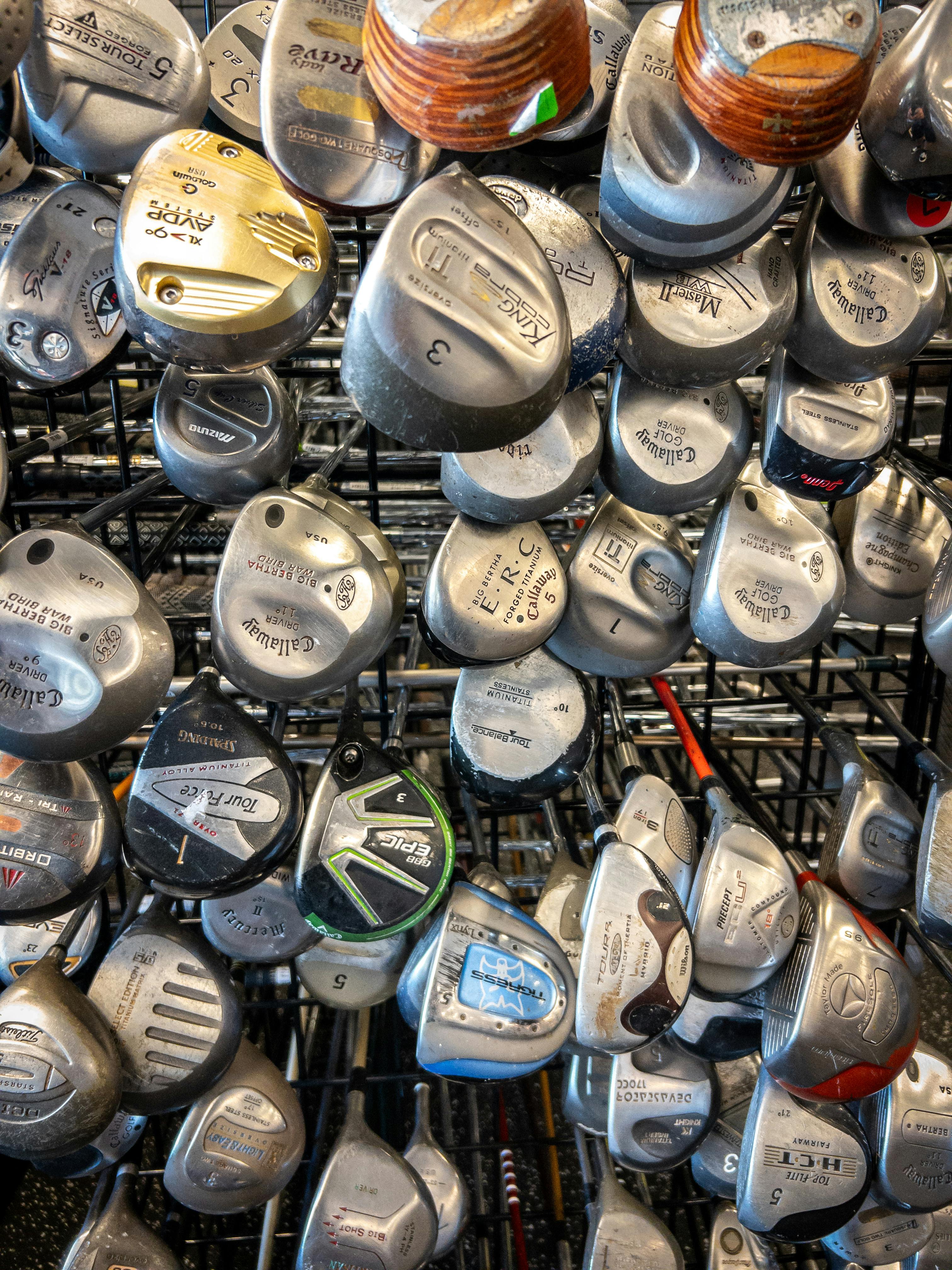 A collection of various used golf club heads in a store display.