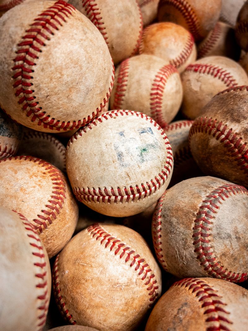 Pile of worn baseballs with red stitching