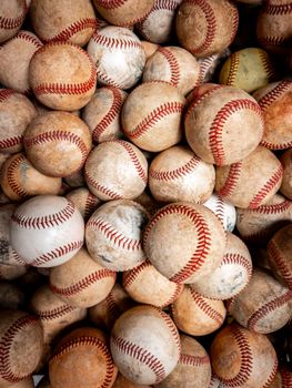 A high-angle view of a heap of old baseballs with red stitching.