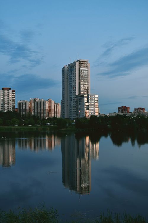 Free High-rise buildings reflecting in calm water at twilight, showcasing modern urban architecture. Stock Photo