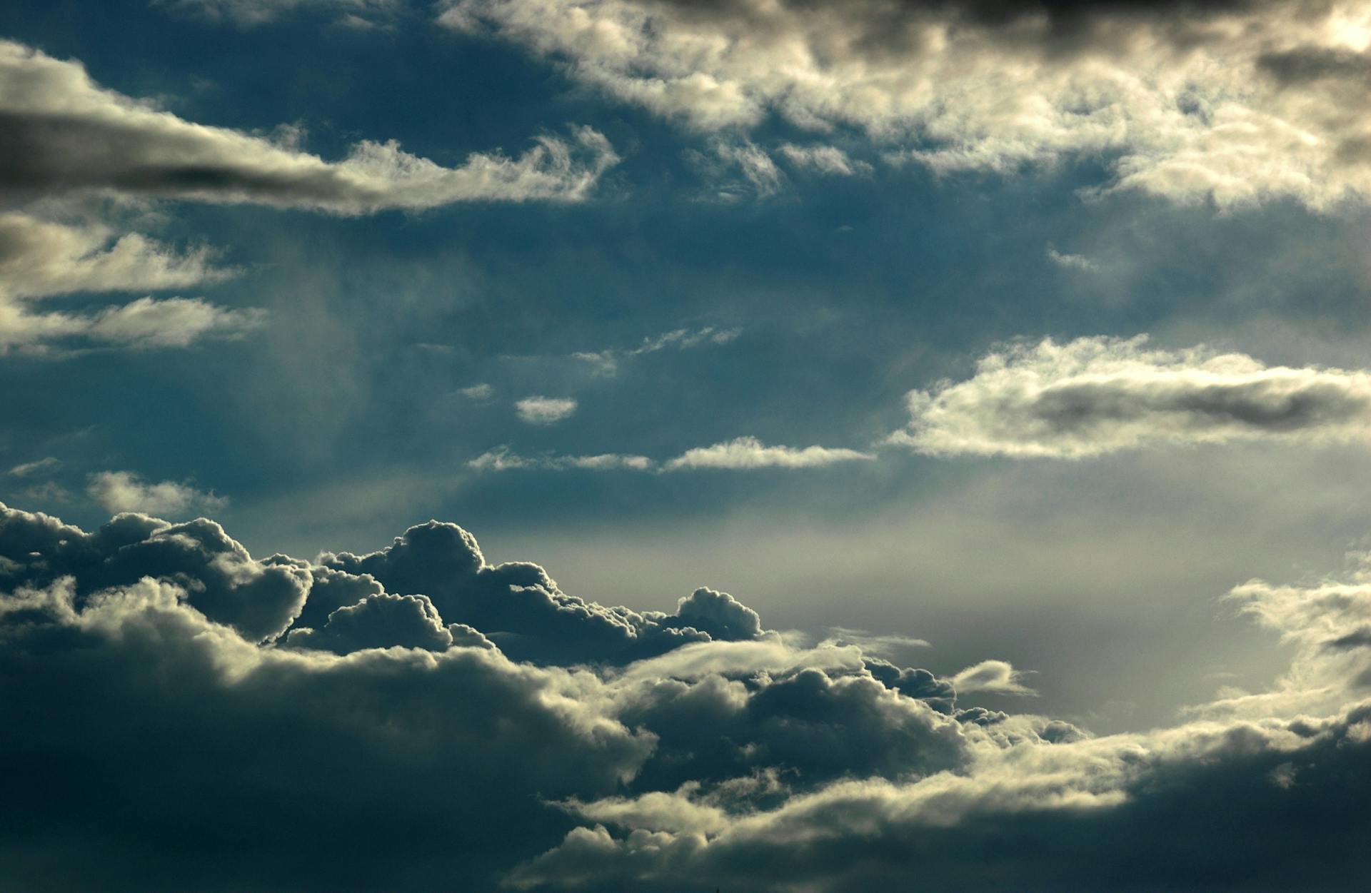 Dramatic cloudscape featuring layered clouds with sunlight breaking through, depicting a captivating sky scene.