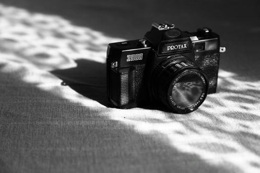 Close-up of a vintage camera with lens, showcasing intricate details and artistic shadows.