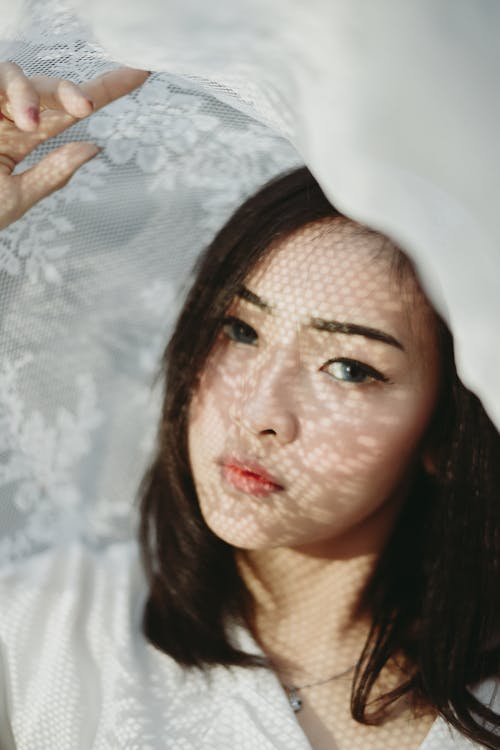 Woman in White V-neck Top Holding White Floral Textile Close-up Photography