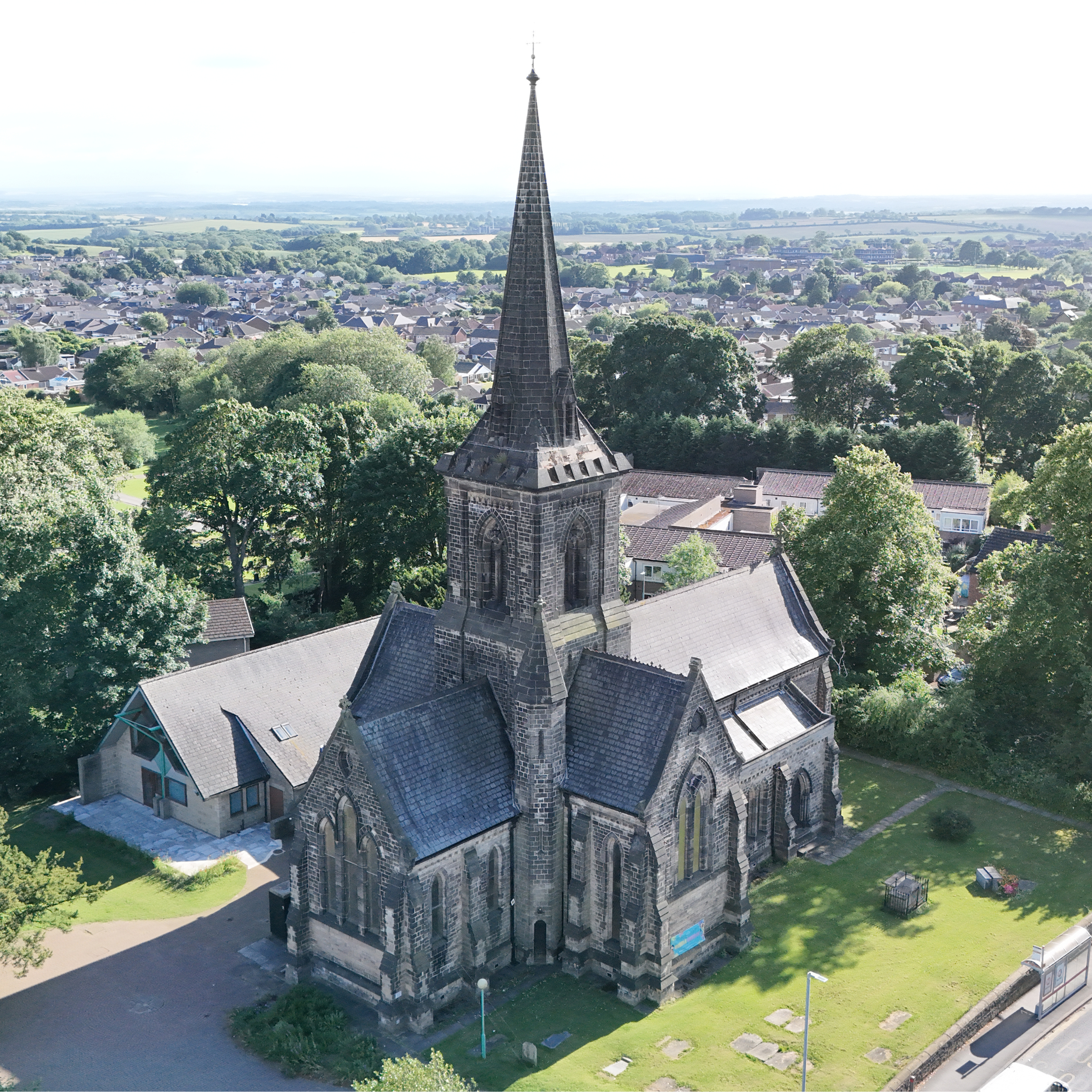 Drone shot of St Mary's Church, Garforth, showcasing Gothic architecture and lush greenery.