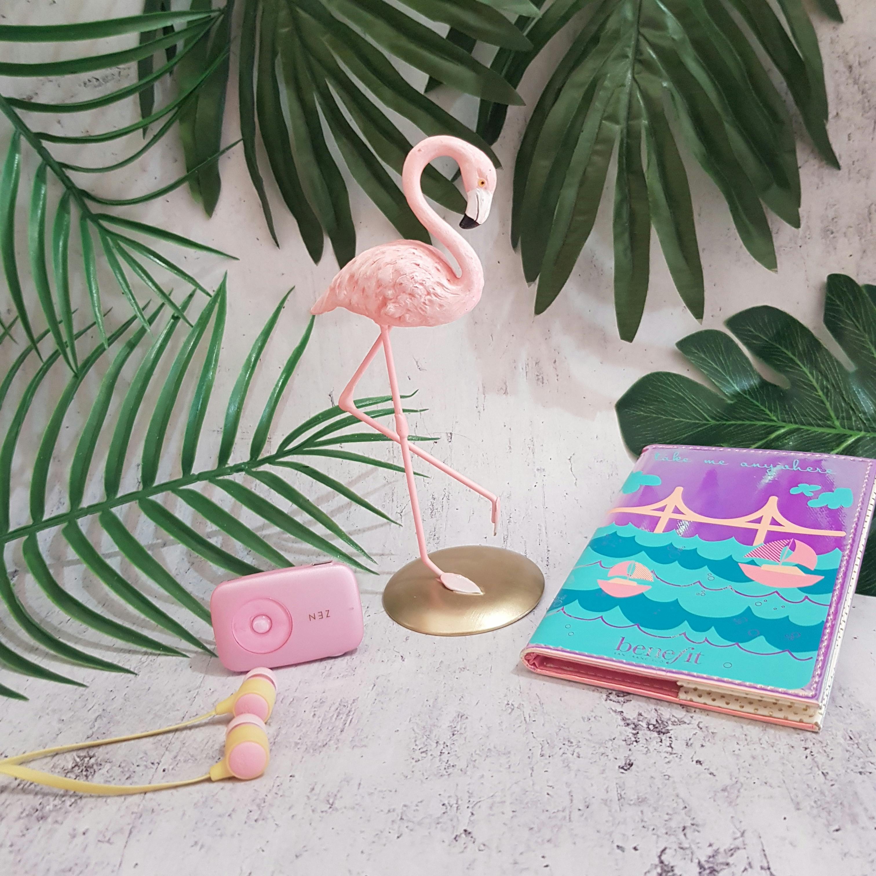 Pink Flamingo Figurine Near Pink Camera, Pink Earbuds, and Photo Album ...