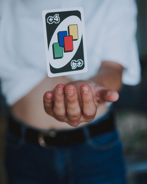 Free Close-up shot of a person tossing an Uno playing card mid-air, highlighting skill and motion. Stock Photo