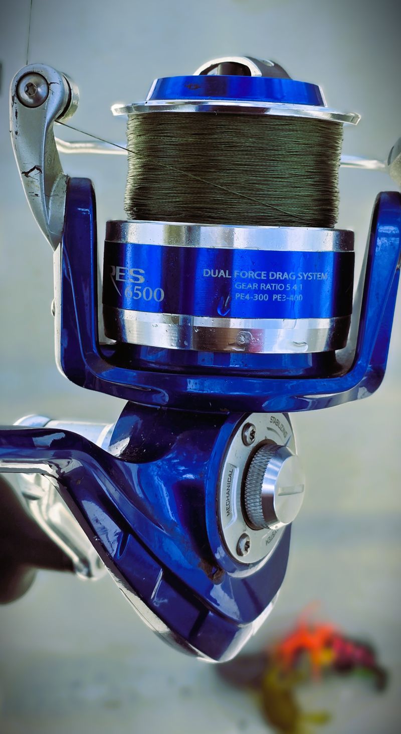 Close-up of a blue spinning reel with fishing line, showing spool fill level