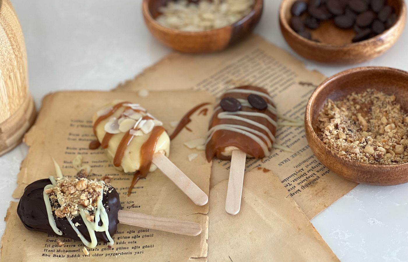 Delicious homemade ice cream popsicles with caramel and chocolate toppings, displayed on vintage paper.