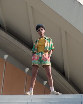 Young woman with afro in vibrant outfit poses confidently outdoors in Berlin.
