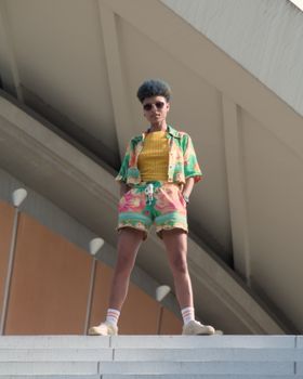 Young woman in vibrant outfit stands confidently against modern architecture in Berlin.