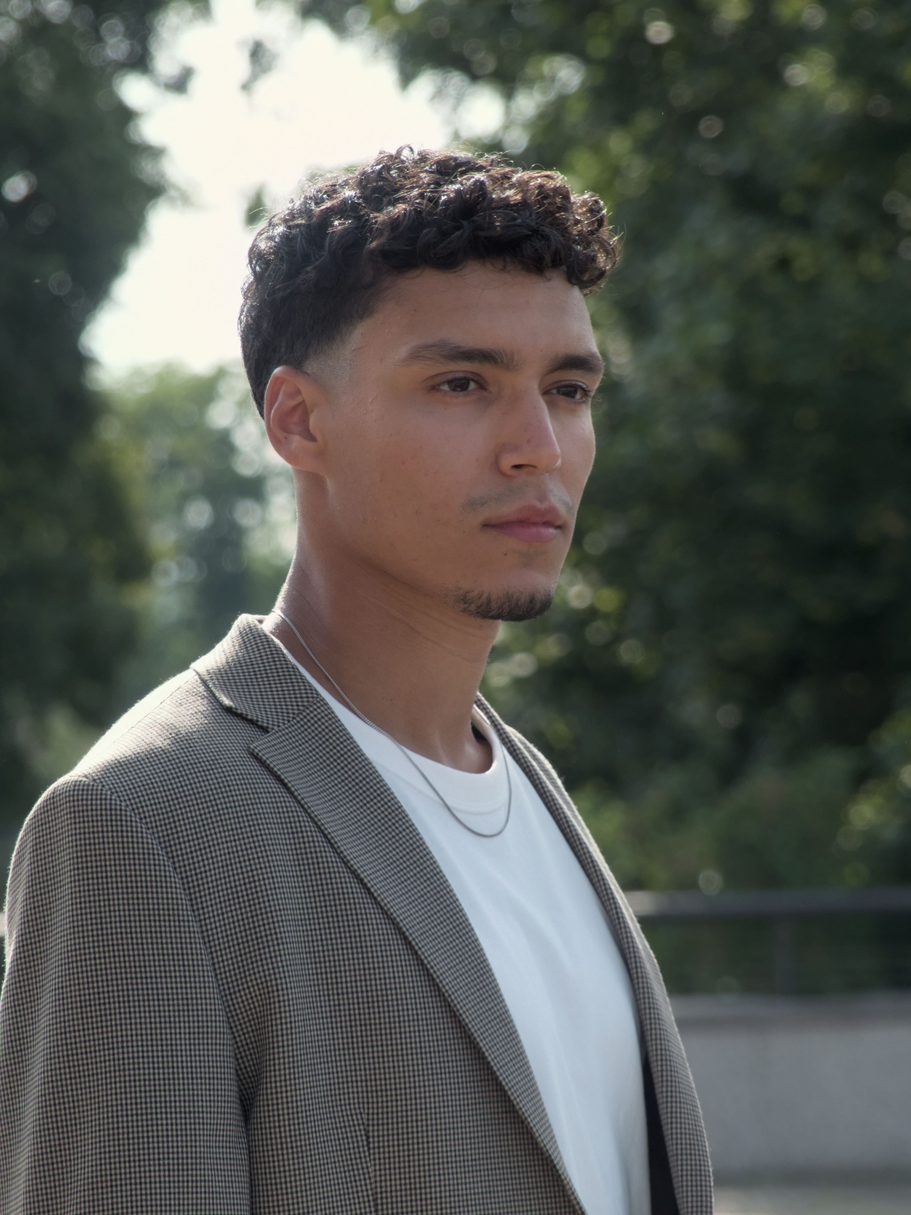 Fashionable young man wearing a blazer and necklace outdoors in Berlin, Germany.