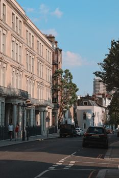 Charming urban street lined with classic buildings under clear blue sky with light traffic.
