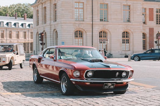 Classic red Ford Mustang parked on a cobblestone street near historic architecture.