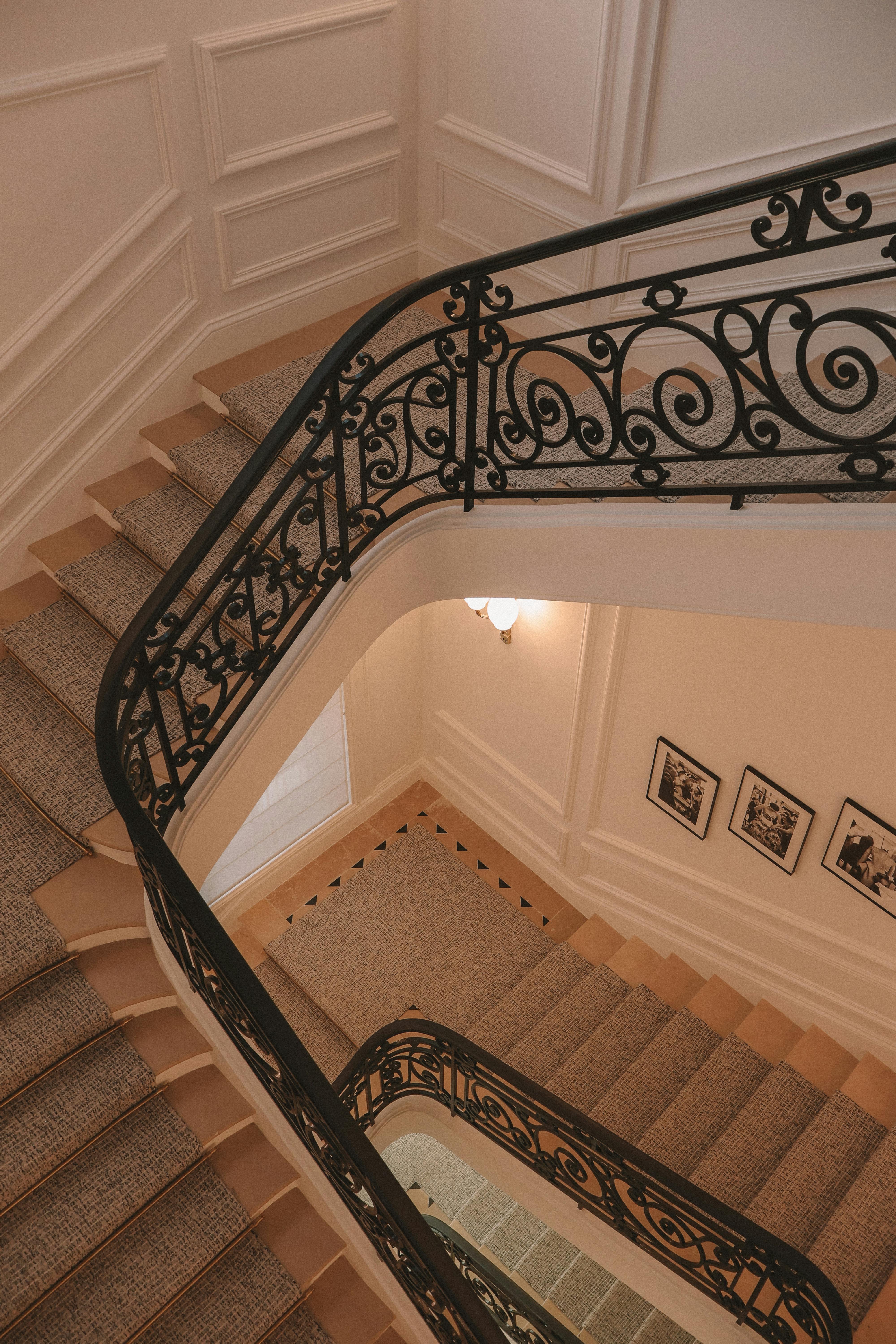 A beautifully illuminated spiral staircase in a classic Parisian building, showcasing intricate ironwork.