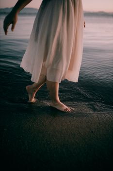 Woman strolling barefoot on sandy beach at sunset, capturing tranquility.