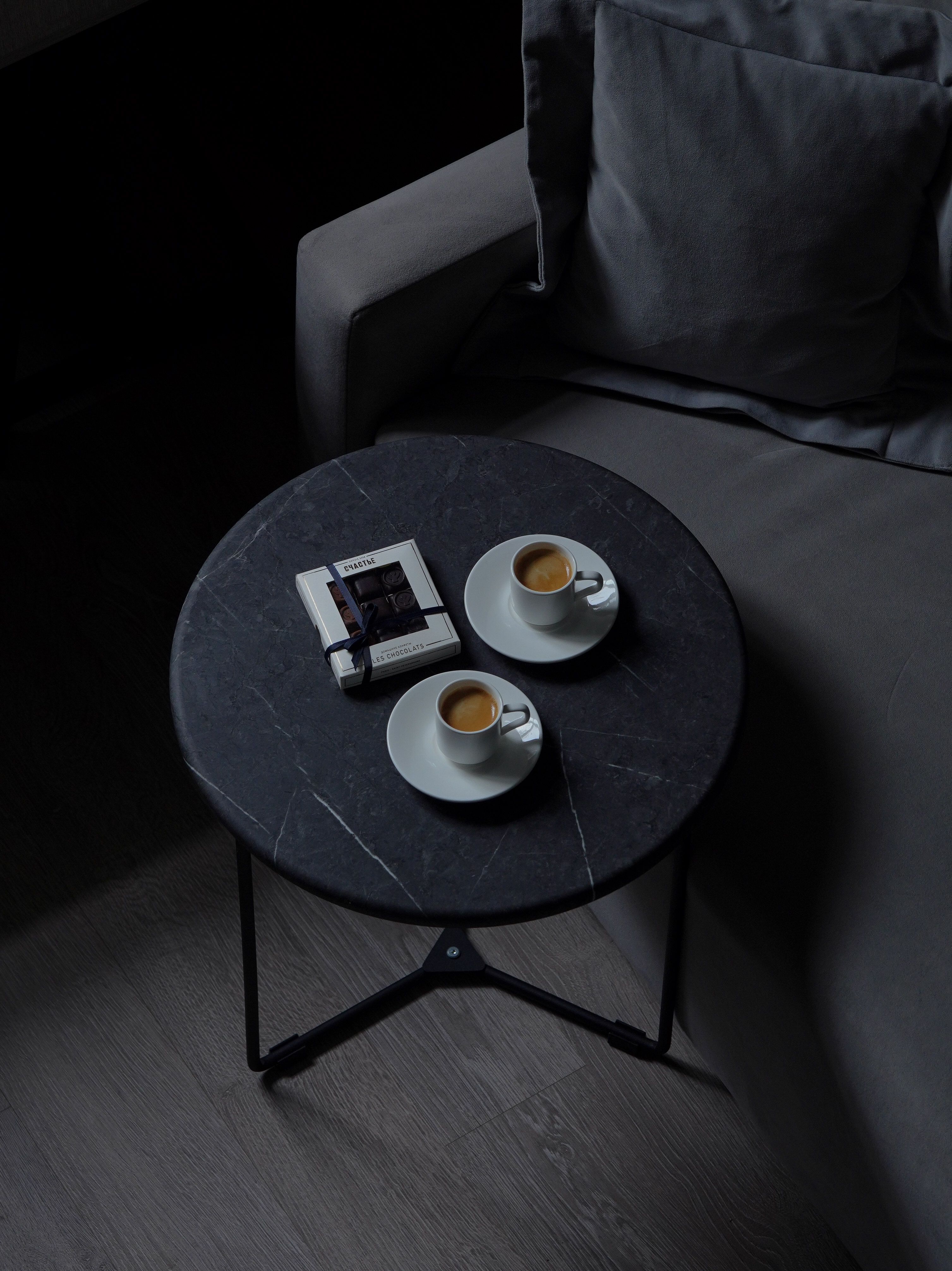 Two espresso cups on a table beside a sofa create a cozy vibe.